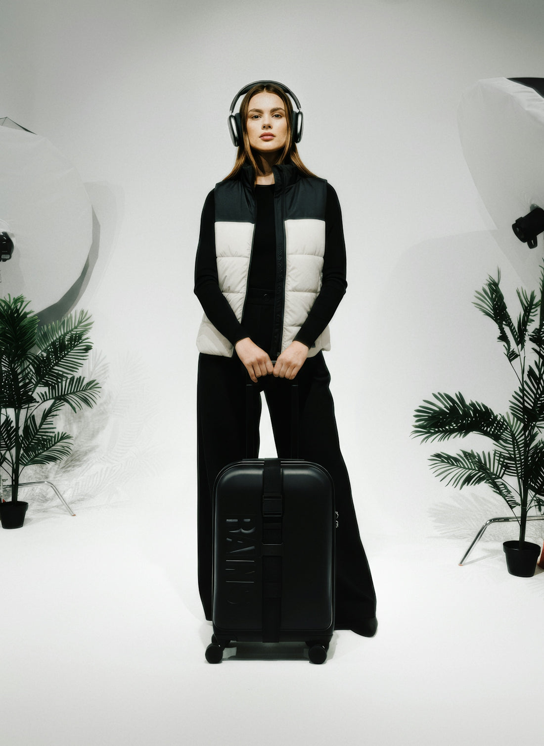 Woman with headphones and suitcase in studio