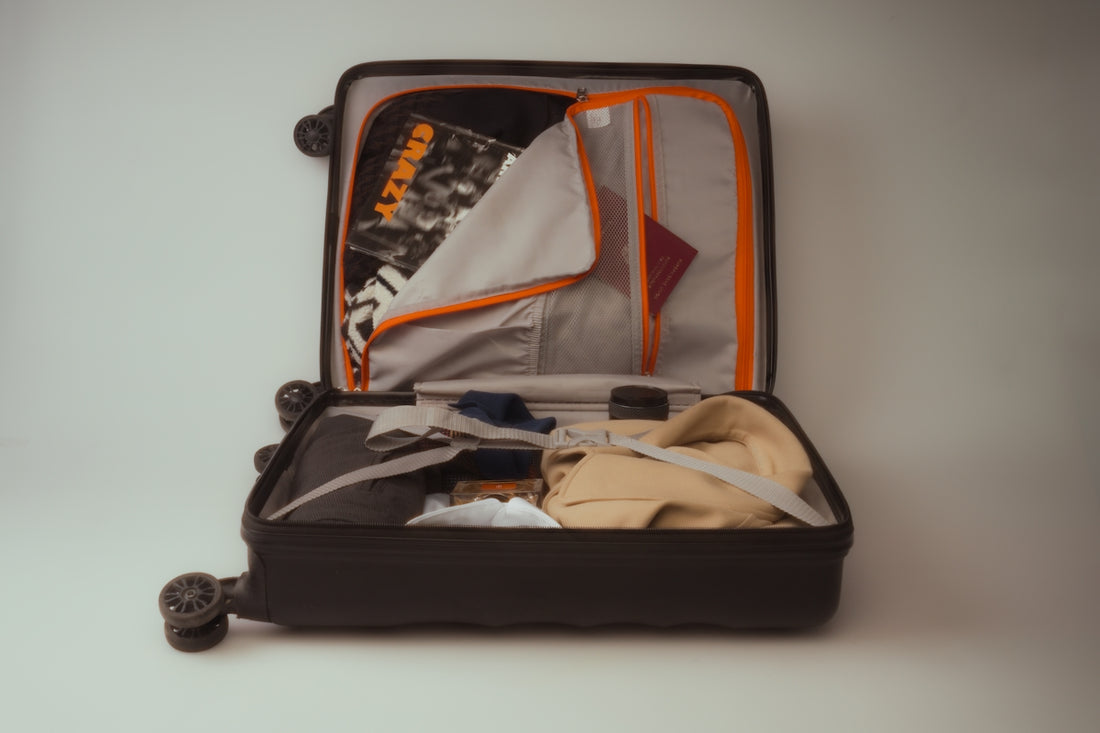 An open black suitcase packed with clothes and travel essentials.